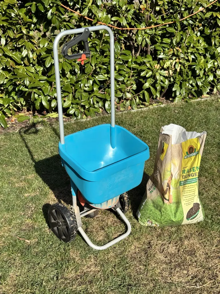 Gardena Streuwagen und Neudorff Azet Rasendünger als optimale Erste-Hilfe-Lösung, wenn der Rasen braun nach Winter ist.