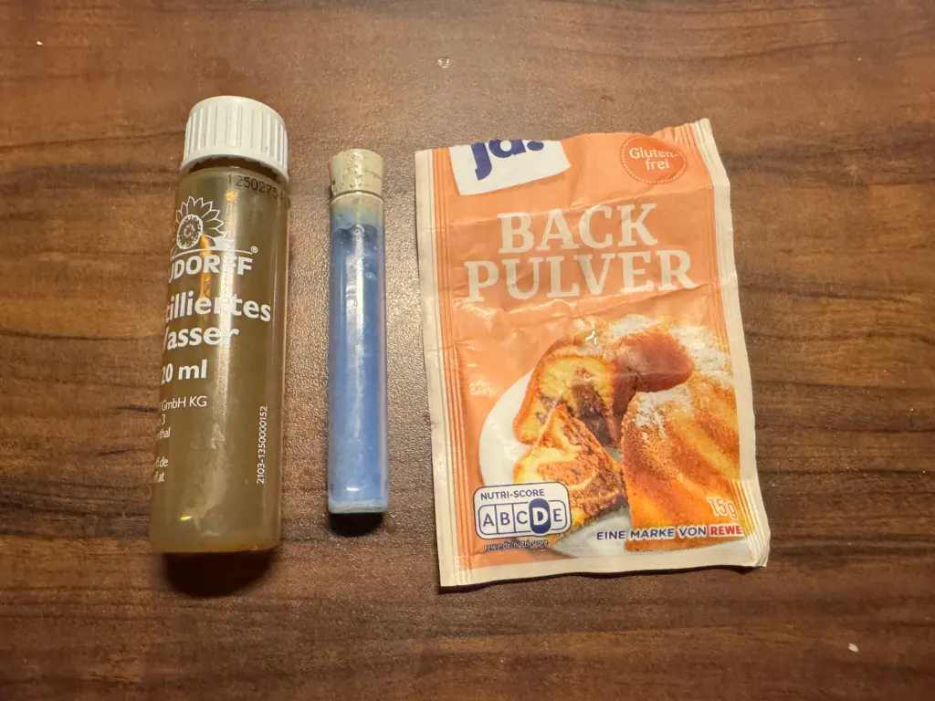 Neudorff pH-Bodentest im Lauge-Stress-Test: Ein Röhrchen mit tiefblauer Flüssigkeit, daneben ein geöffnetes Päckchen ja! Backpulver (Marke von REWE) auf Holzuntergrund.