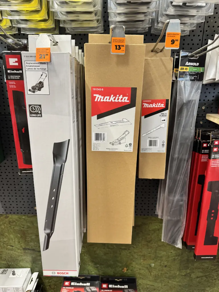 Ein Baumarkt Regal mit verschiedenen Rasenmähermessern als Ersatz. Für meinen DLM432 kostet das Ersatzmesser dort "nur" 13,95 Euro. Daneben hängen Ersatzmesser für Bosch oder Makita oder Einhell.