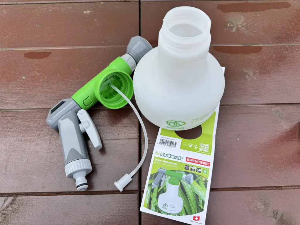Der Birchmeier Multikraft Dünger-/Wassermischer 1,25 - der Aufsatz liegt neben der Flasche und es ist noch das Etikett zu sehen, welches auf der Rückseite die Bedienungsanleitung enthält.