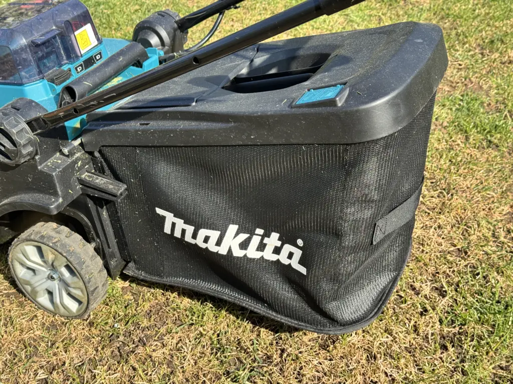 Makita DLM432 Akku-Rasenmäher mit montiertem Fangkorb auf dem Rasen.