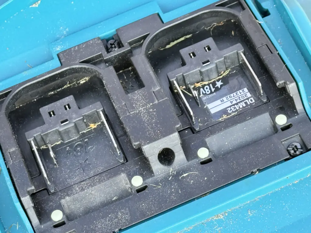 Die beiden Akkuschächte des Makita DLM432 liegen direkt nebeneinander unter einer Kunststoffhaube.