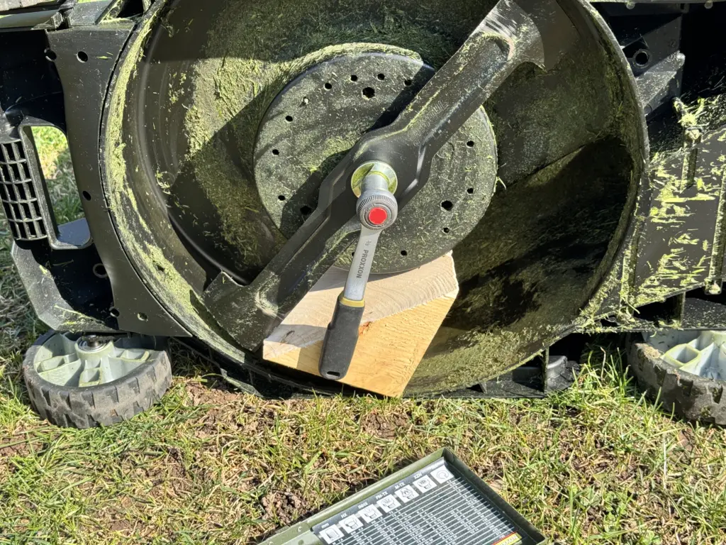 Das Rasenmähermesser des Makita DLM432 ist mit einem Holzkeil blockiert - die Ratsche des Proxxon Steckschlüsselsatzes hängt an der Schraube (17er SW), und kann nun einfach gelöst werden.