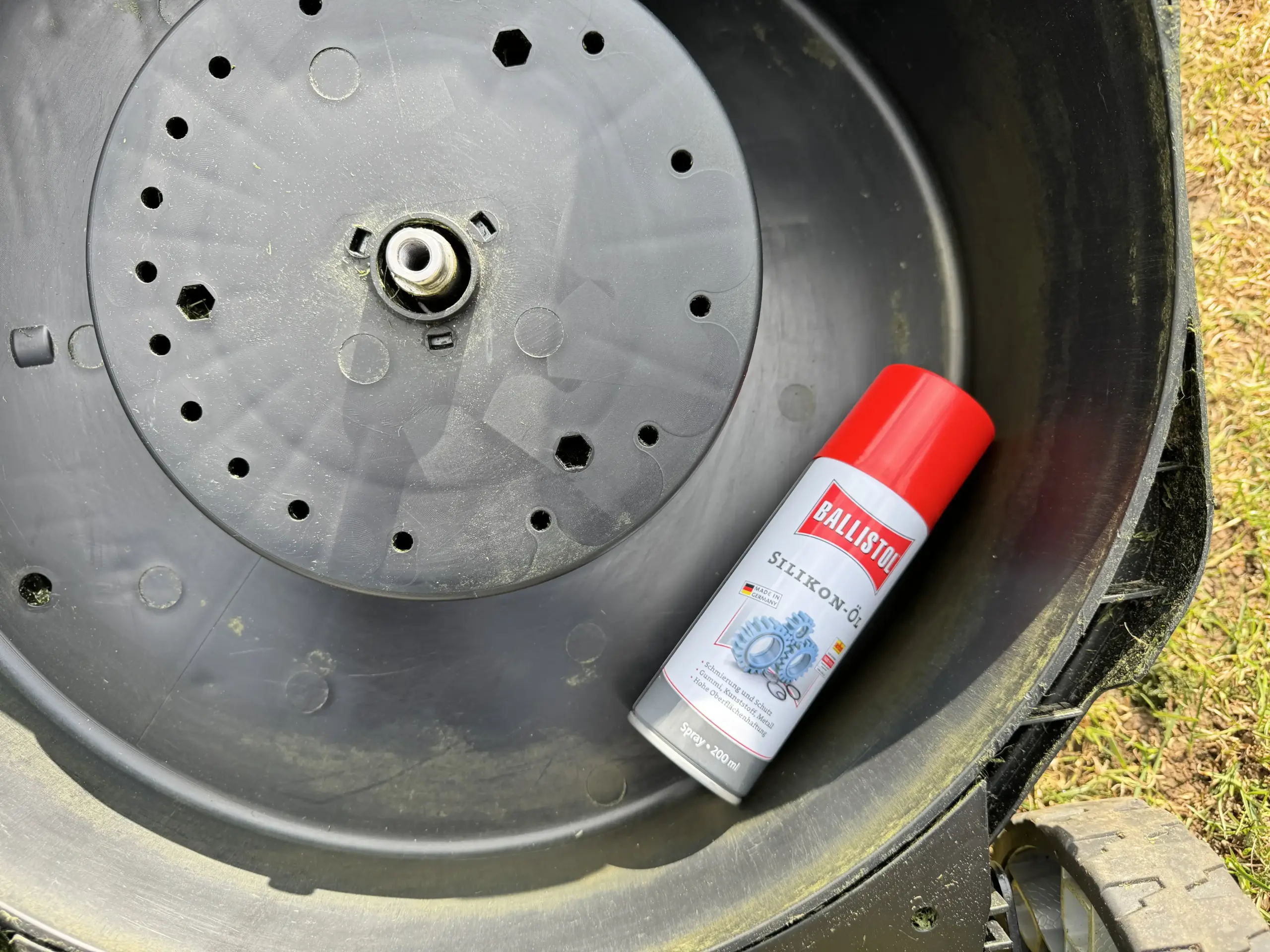Eine Flasche Ballistol Silikon-Öl-Spray liegt im sauberen Mähdeck meines Rasenmähers.