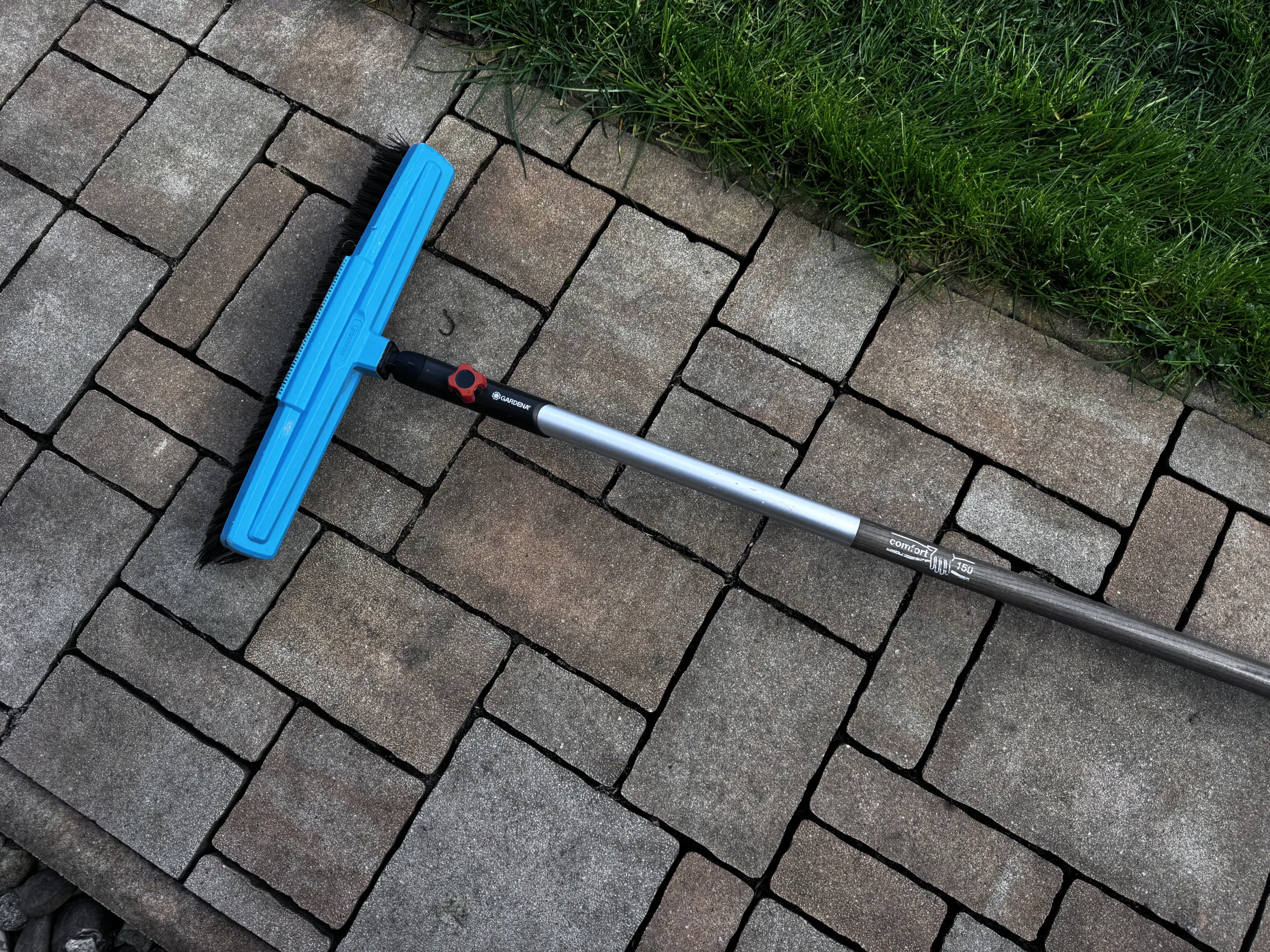 Gardena Combisystem Besen wird von seinem Stiel getrennt, um platzsparend an der Holzwand verstaut zu werden.