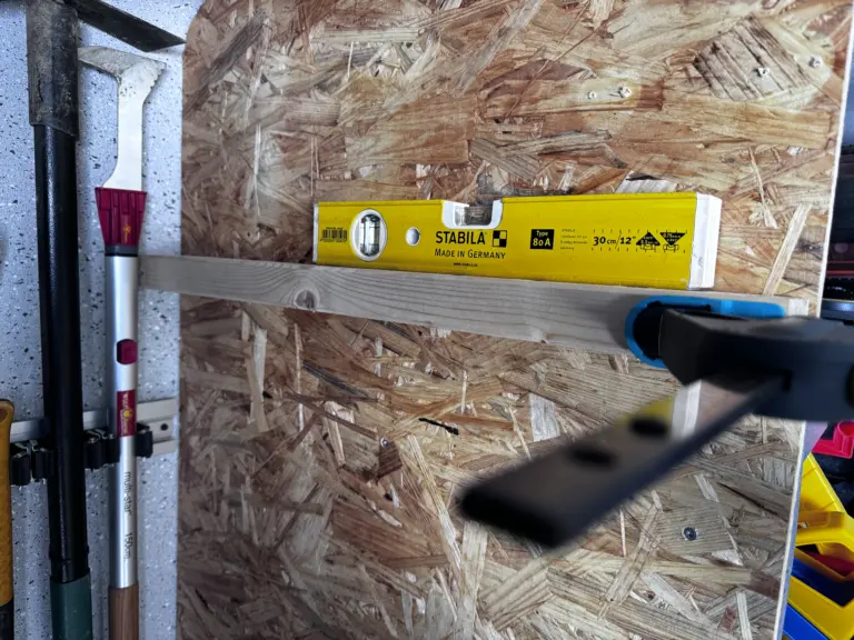 Holzleiste für Kleingeräte mit Wasserwaage und Schraubzwinge an der OSB-Wand ausgerichtet