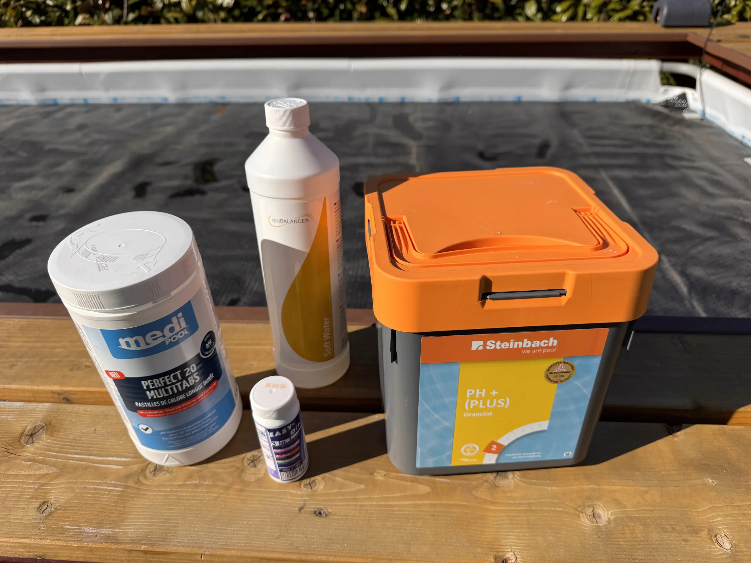 Ein medi Perfect 20 Multitabs, Softwater, Ratestäbchen zur pH-Wert-Messung und ein pH+ (Plus) Behälter stehen auf meiner Poolumrandung - Poolwasser einstellen ist damit nicht perfekt möglich