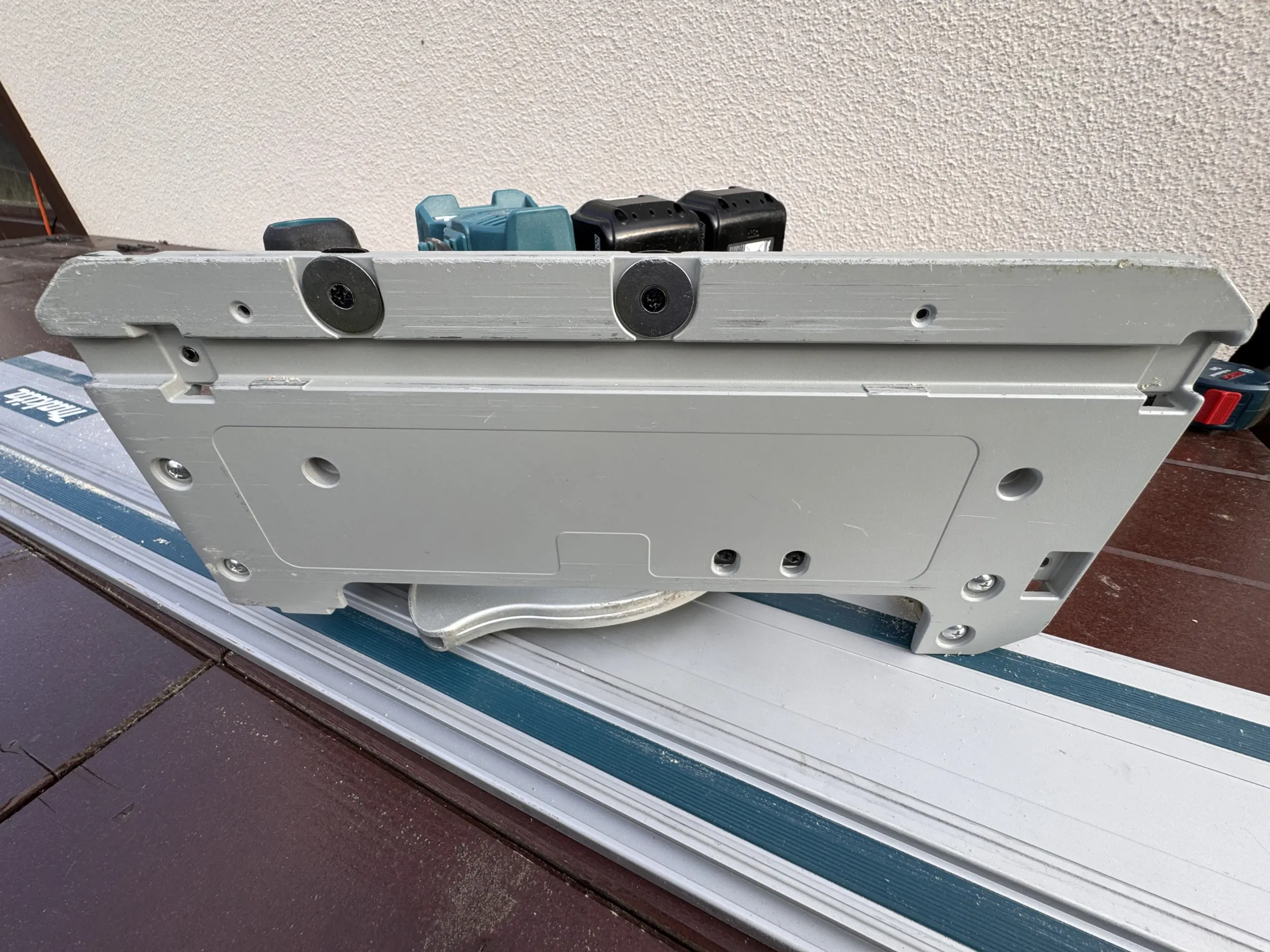 Eine Makita DHS900 Grundplatte liegt auf einer Makita Führungsschiene - man erkennt die Führung der Makita Handkreissäge, die schon leicht zerkratzt ist..