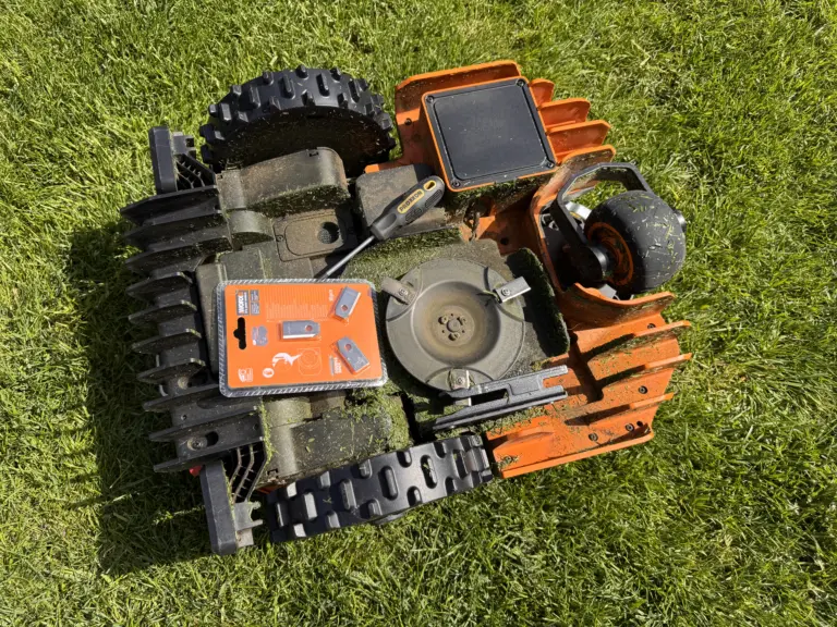 Mähroboter Unterseite – Messer, Räder und Wartung Unterseite eines Worx Mähroboters mit Messerteller, Rädern und Grasresten