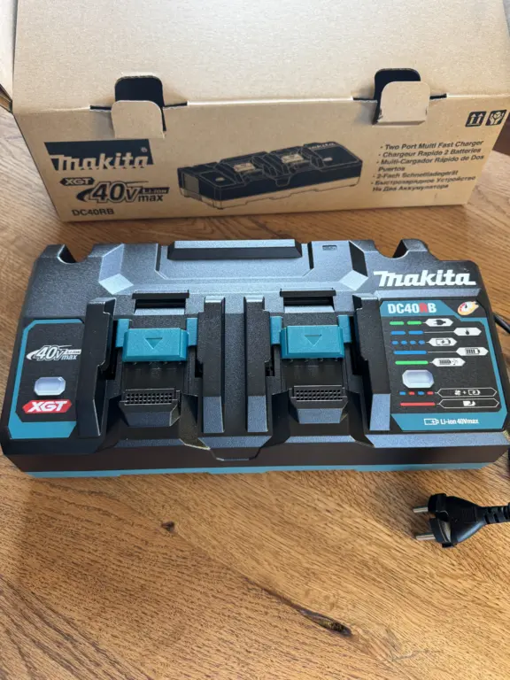Makita DC40RB XGT Doppelladegerät auf Holztisch mit Originalverpackung