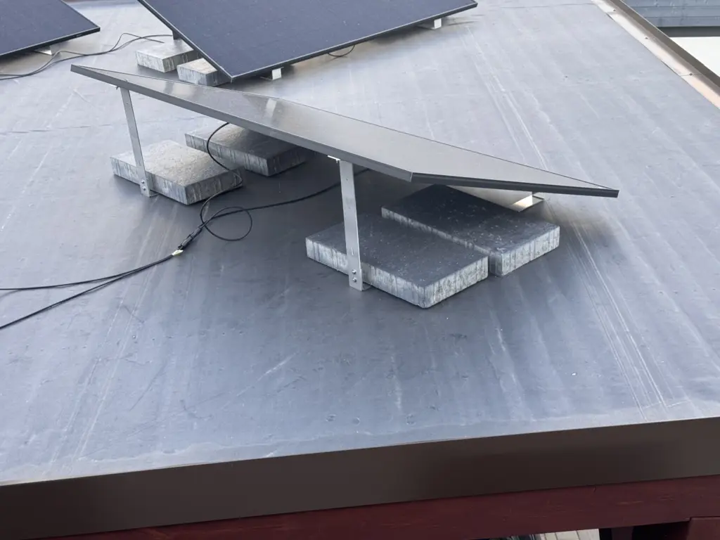 Aufgeständertes Solarmodul auf dem Carport mit schweren Terrassenplatten als Ballast