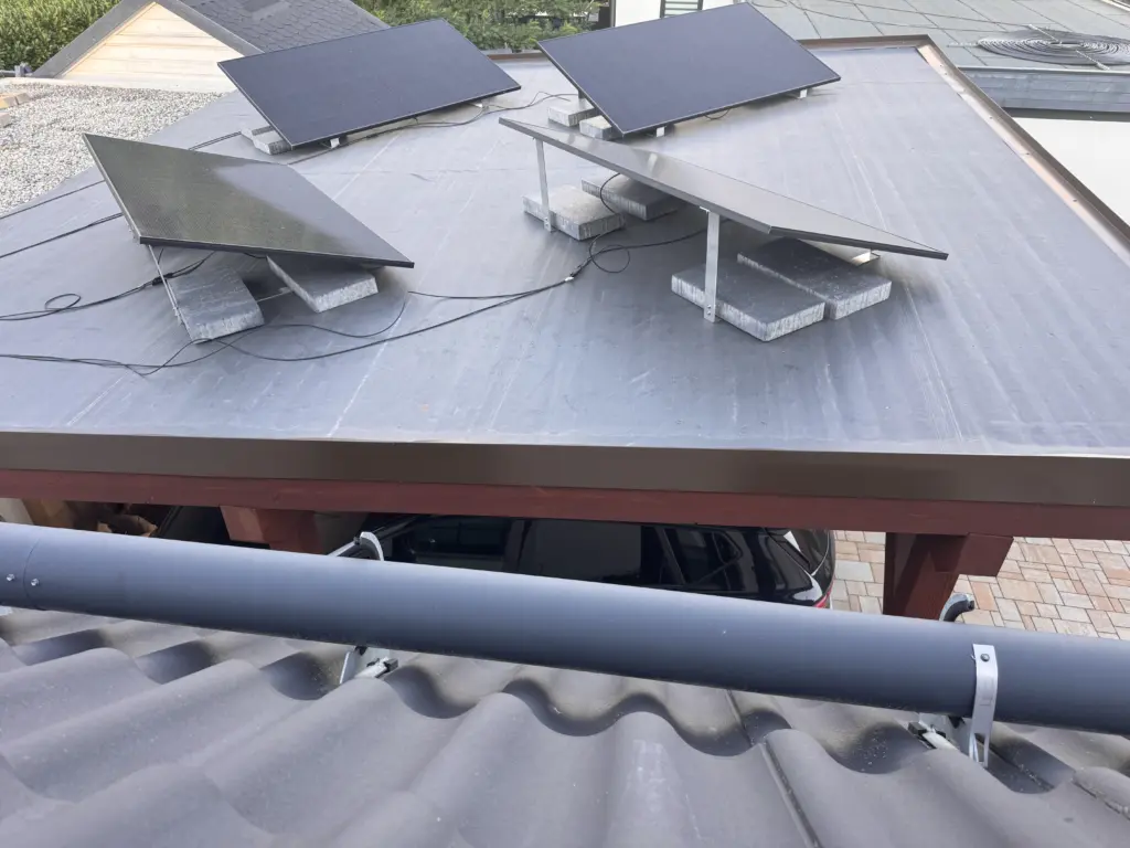 Vier Solarmodule mit unterschiedlicher Ausrichtung auf einem Carport-Flachdach