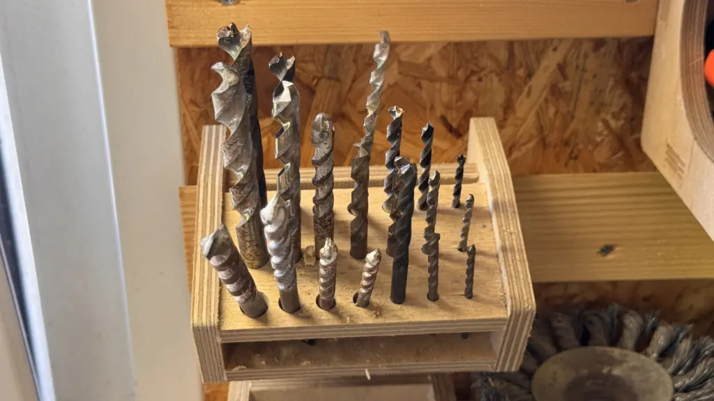 Offen gelagerte gebrauchte Bohrer in einem selbst gebauten Holzhalter im Schuppen