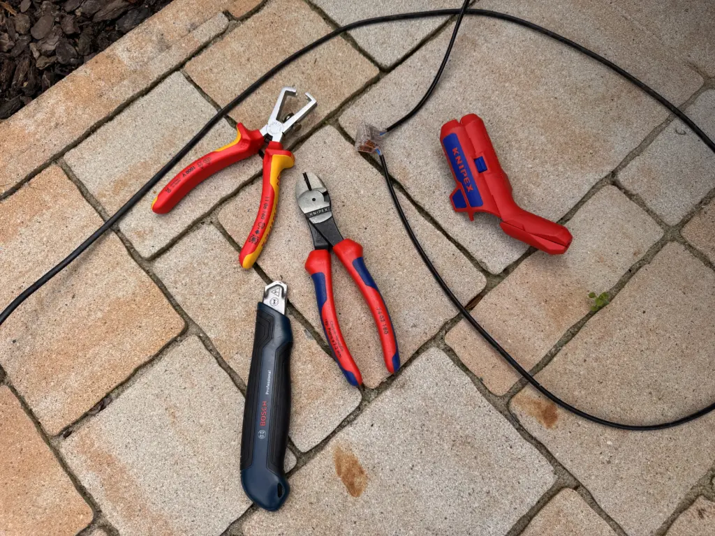 Knipex ErgoStrip, Knipex Seitenschneider und Abisolierzange neben dem Kabel einer Worx Ladestation