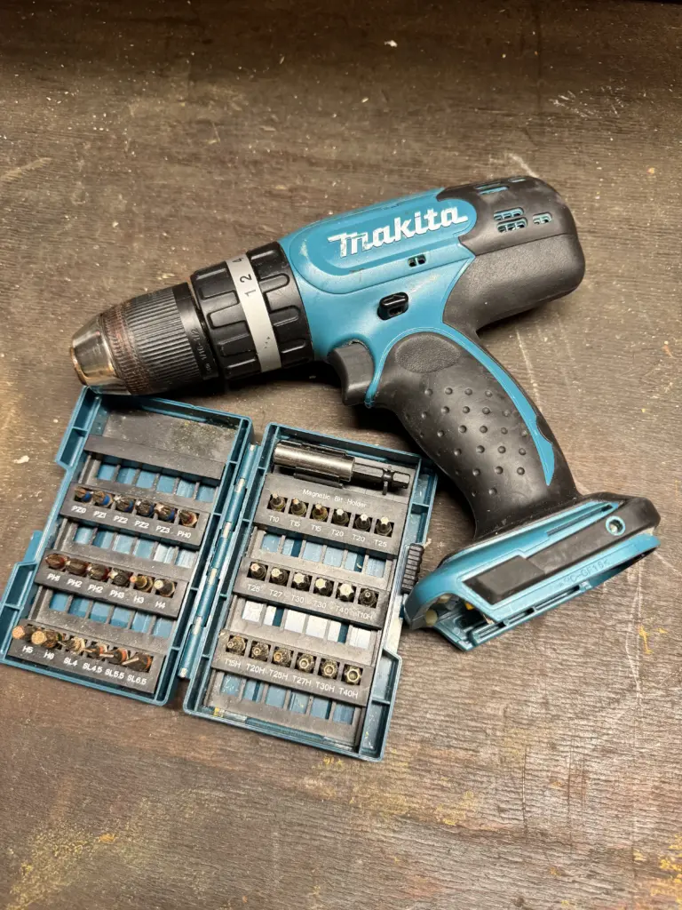 Makita DHP453 Akku-Schlagbohrschrauber mit geöffnetem Bit-Set auf einer Werkbank
