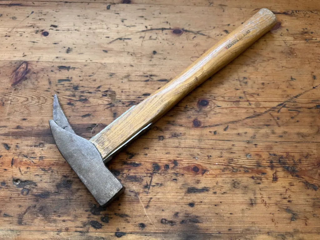 Gebrauchter Zimmermannshammer mit Holzstiel auf einer alten Werkbank