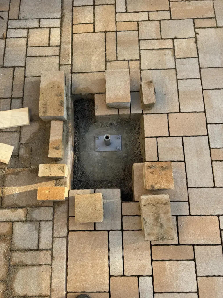 Freigelegtes Carport-Fundament in der Pflasterfläche mit montiertem Pfostenträger