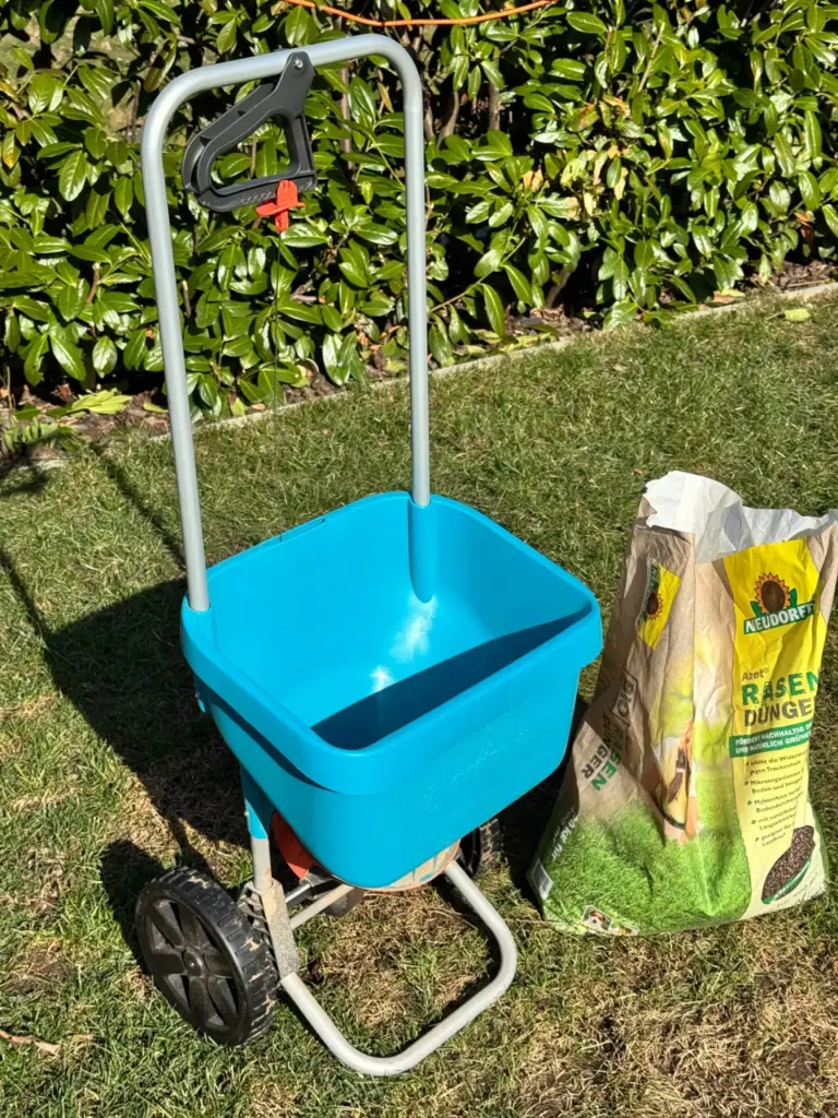 Streuwagen oder Schleuderstreuer: mein blauer Gardena XL neben einem geöffneten Sack Neudorff Azet Rasendünger auf dem Rasen