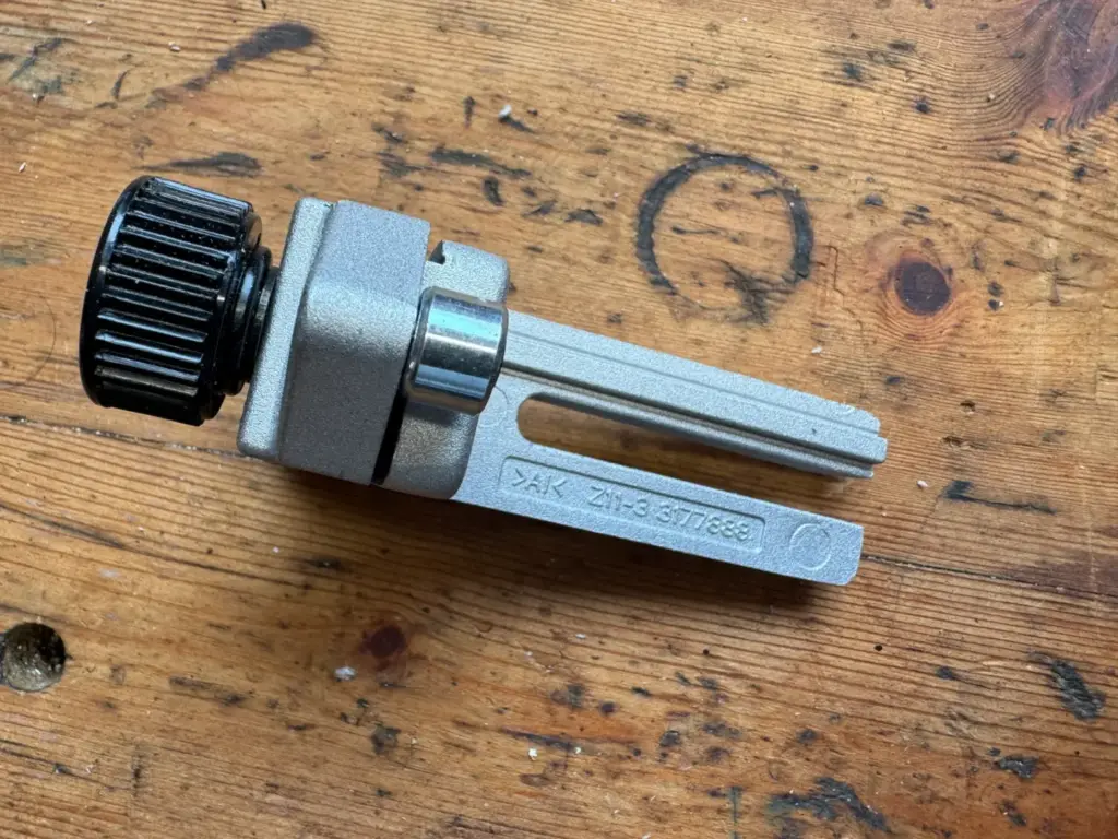 Rückseite der Makita DRT50 Kantenführung mit Langloch, Metallrolle und Einstellrädern