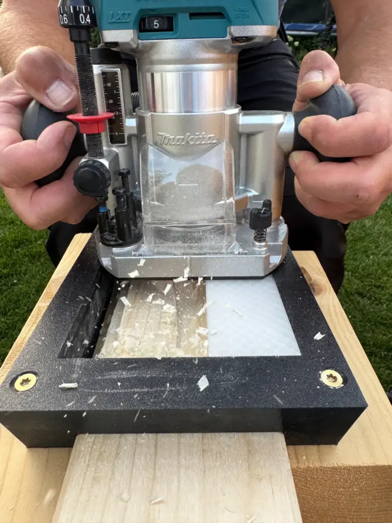 Makita DRT50 im Oberfräsenmodul beim Fräsen mit schwarzer Schablone