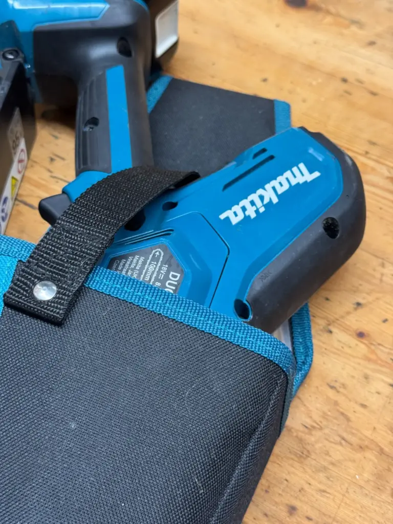 Makita DUC101 im Holster 1913K4-9 mit Sicherungsriemen über dem Motorgehäuse