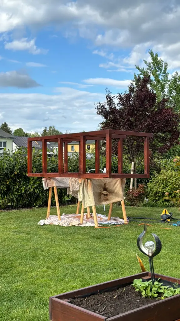Braun gestrichenes Rahmenbauteil der Mülltonnenbox auf Arbeitsböcken im Garten