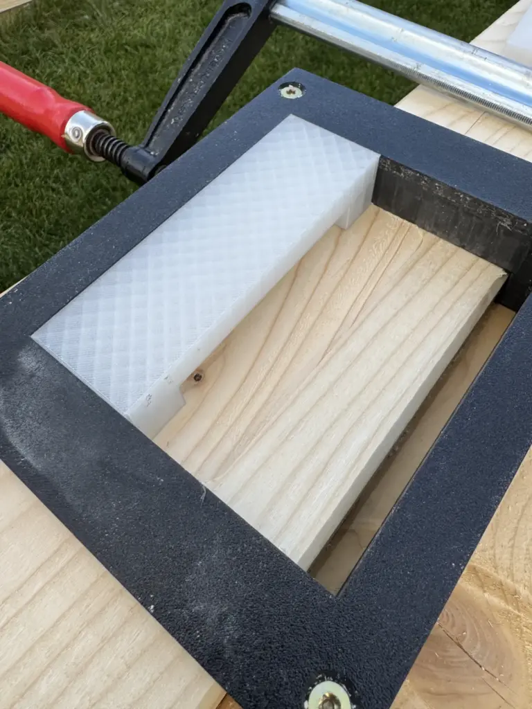 Schwarze Frässchablone mit weißem 3D-gedrucktem Einsatz auf einem 10 x 20 cm Sparren