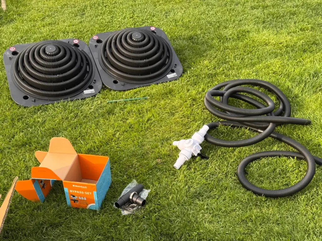 Zwei Steinbach Loop Solarkollektoren mit Bypass und schwarzen 32-mm-Poolschläuchen vor der Montage