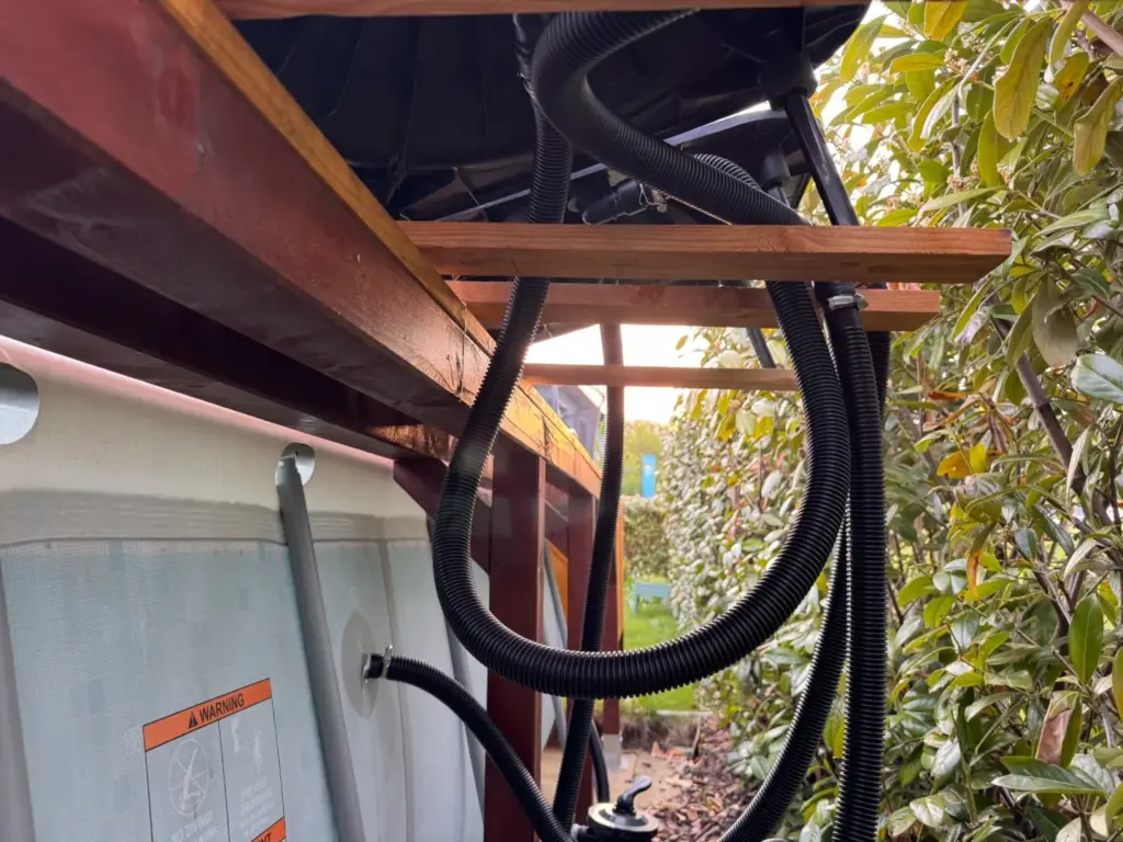 Schwarze Poolschläuche und Anschlüsse unter den montierten Steinbach Loop Solarkollektoren