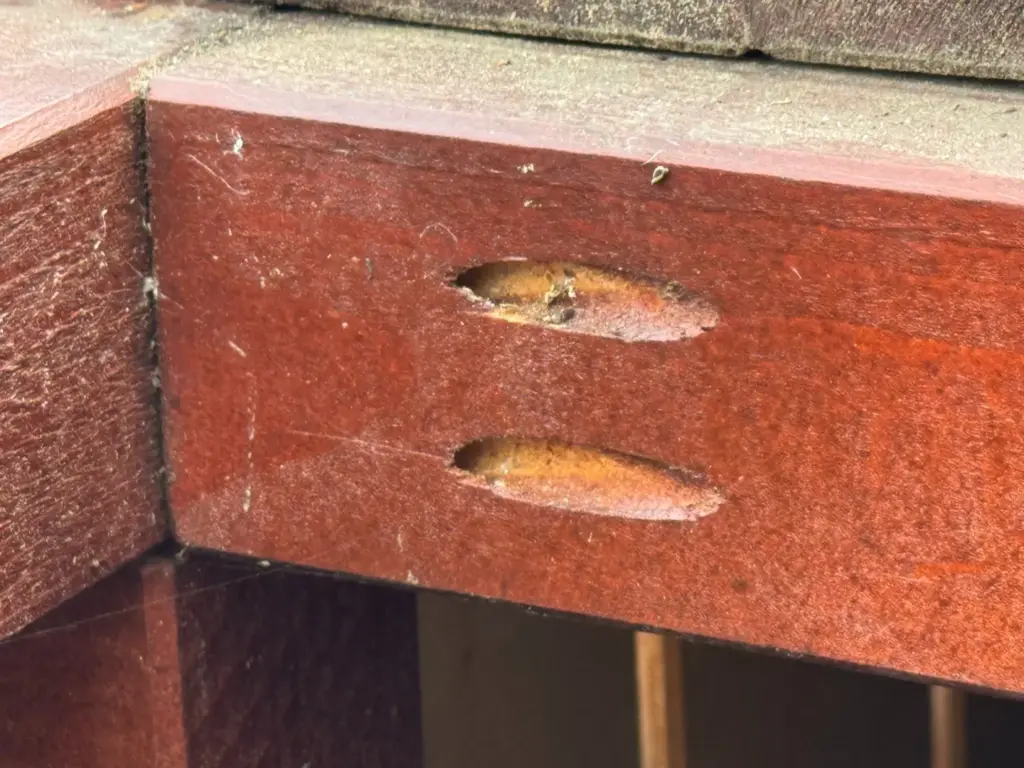 Innen bewusst offen gelassene Taschenlochbohrungen am Holzrahmen der Mülltonnenbox