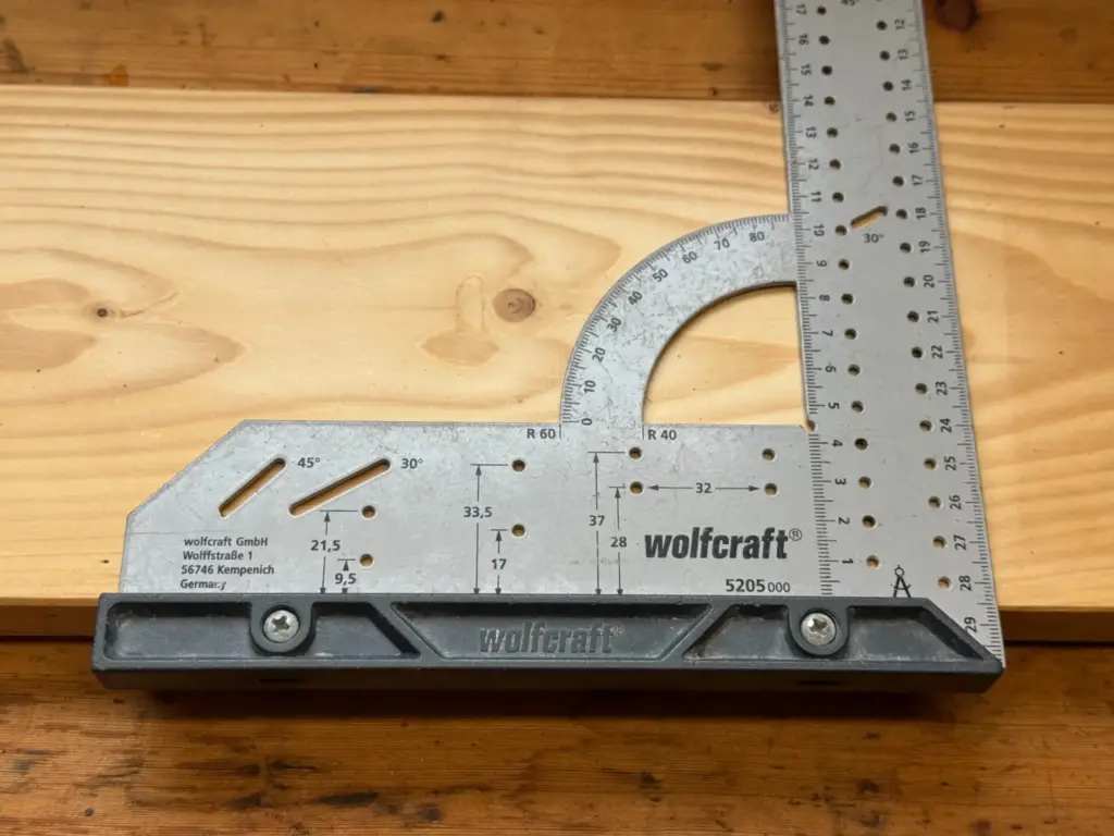 Silberner wolfcraft Universalwinkel 5205000 mit Winkelskala, 30- und 45-Grad-Schlitzen sowie 32-mm-Markierlöchern auf Holz