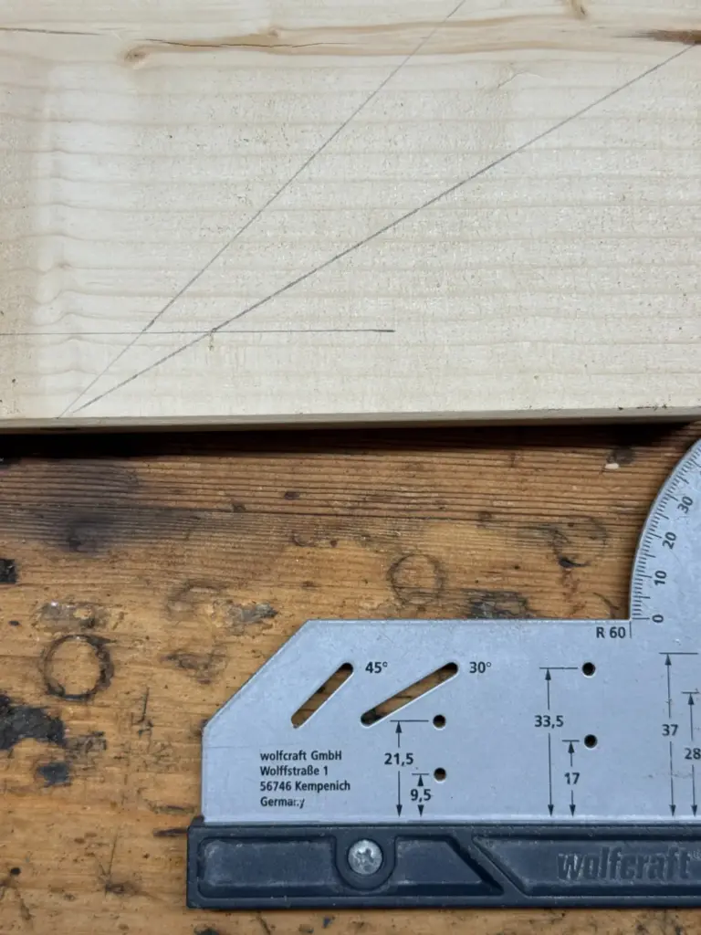 Holzbrett mit mehreren Bleistiftlinien neben dem wolfcraft Universalwinkel 5205000