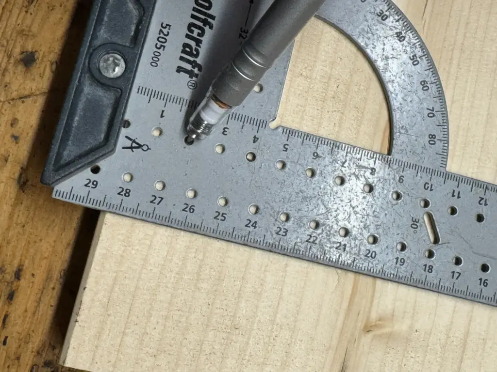 Nahaufnahme der Millimeterskala des wolfcraft Universalwinkels 5205000 mit Bleistiftspitze nahe Markierlöchern